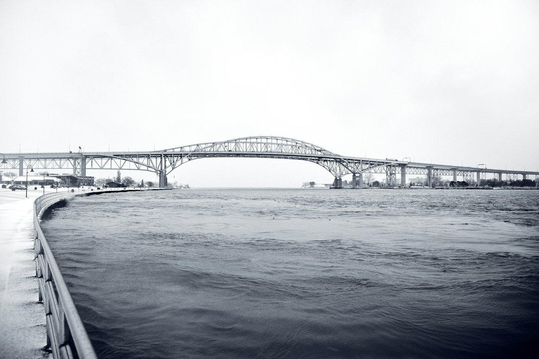 Grayscale photo of an international bridge over water on the Canada-US border corridor