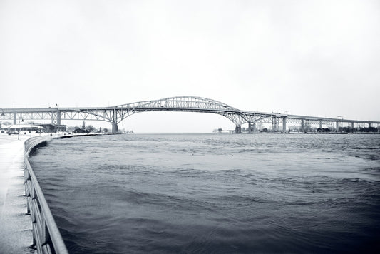 Grayscale photo of an international bridge over water on the Canada-US border corridor