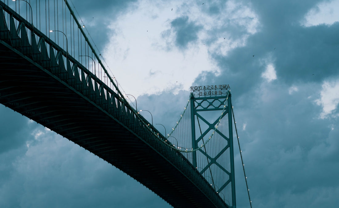 black suspension bridge — cross-border freight (Unsplash, Hermes Rivera)