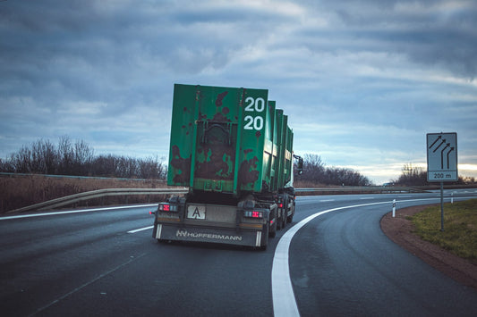 Green freight truck on a winding highway heading toward the Canada border