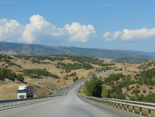 Truck driving along a road with mountains in the background